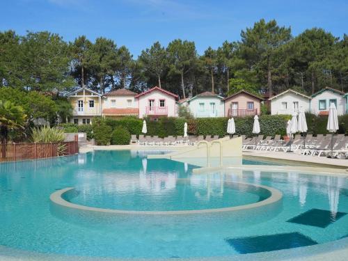 a large swimming pool with chairs and umbrellas at Holiday Home Domaine Golf Resort-2 by Interhome in Lacanau-Océan