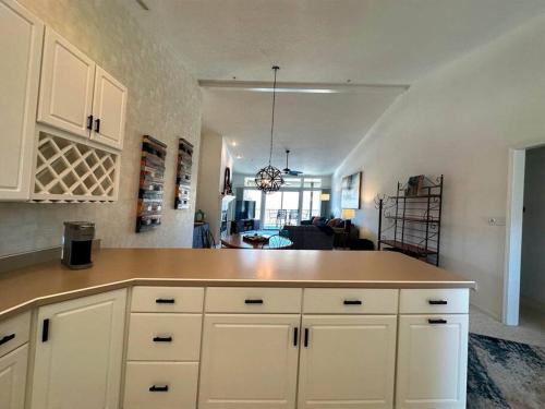 a kitchen with white cabinets and a living room at The Pointe at Lazy Days in Osage Beach