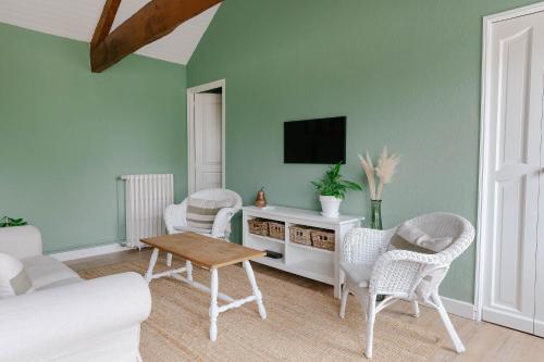 - un salon avec 2 chaises et une télévision murale dans l'établissement Ferme des Goupillières, à Maisons