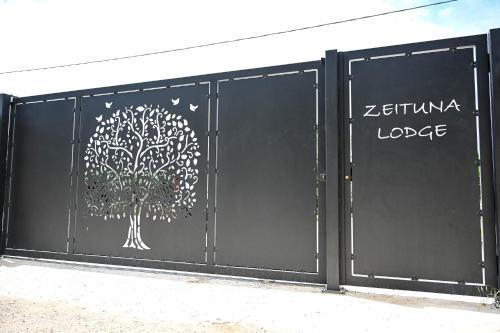 a black gate with a tree painted on it at Zeituna Lodge a Porto Cesareo in Torre Lapillo