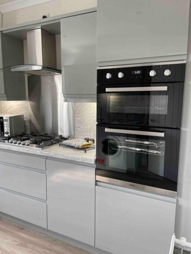 a kitchen with white cabinets and a black oven at Lovely 2 bed apartment with hot tub log burner and off street parking in Dumfries