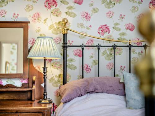 SarnにあるApartment Llofft Sarn by Interhomeのベッドルーム1室(ピンクの花が飾られた壁のベッド1台付)