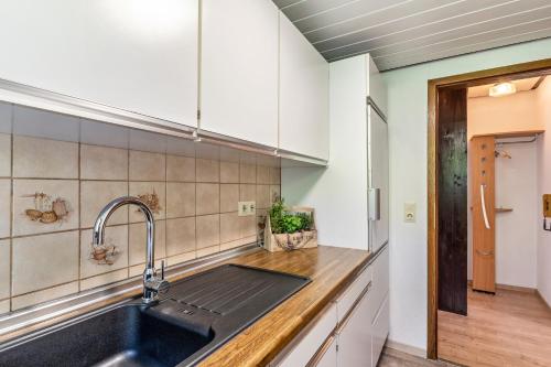 uma cozinha com armários brancos e um lavatório em Heidi Kimmig em Bad Griesbach
