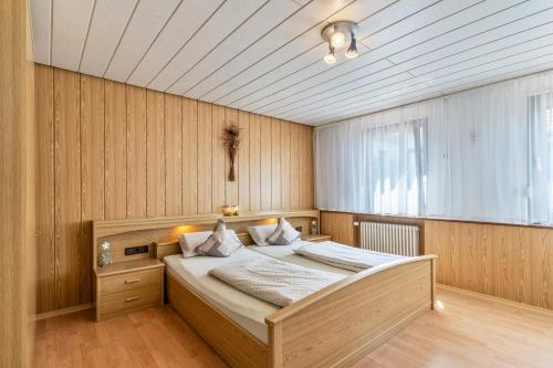 ein Schlafzimmer mit einem Bett in einem Zimmer mit Holzwänden in der Unterkunft Heidi Kimmig in Bad Griesbach