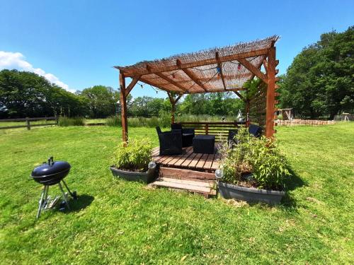 - un kiosque en bois avec un grill dans un champ dans l'établissement Jolie roulotte au bord de la mare, à La Bretauche