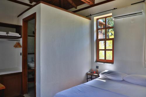 a bedroom with a white bed and a window at Eski Yeni Tatil Evi Olympos in Olympos
