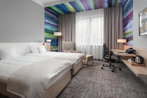 a hotel room with two beds and a desk at Park Hotel & Restauracja Browar Brzeg in Brzeg