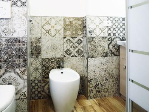 a bathroom with a toilet and a tile wall at HOTEL RESIDENCE VILLA NINA in Spotorno