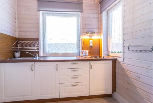 a kitchen with white cabinets and a window at ASTORIA-Ruszel domki letniskowe in Dziwnów