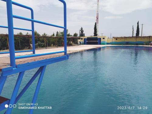 una gran piscina de agua con barandilla azul en Chalets ITO Atlas Timnay en Midelt