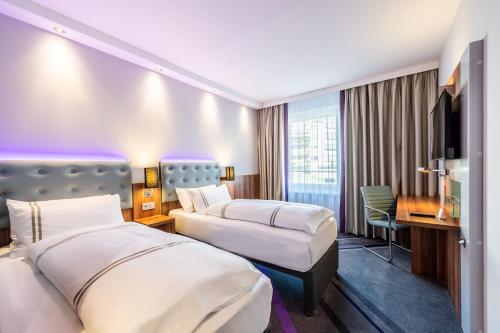 ein Hotelzimmer mit 2 Betten und einem Schreibtisch in der Unterkunft Premier Inn Düsseldorf City Centre in Düsseldorf