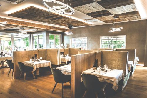 a dining room with tables and chairs and windows at Wiesenhof Gardenresort in San Leonardo in Passiria