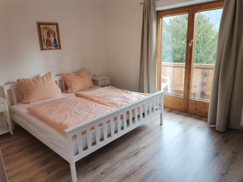 a bedroom with a white bed and a large window at Ferienwohnung Hochstaufen - Chiemgau Karte in Inzell