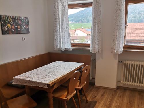 a table and chairs in a room with two windows at Ferienwohnung Hochstaufen - Chiemgau Karte in Inzell
