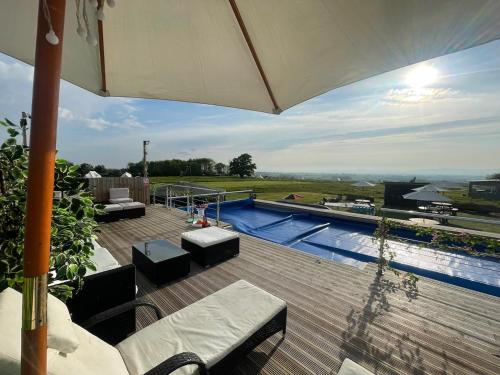 eine Terrasse mit einem Sonnenschirm und einem Pool in der Unterkunft Swallow Perch, Willow Hill in Gloucester