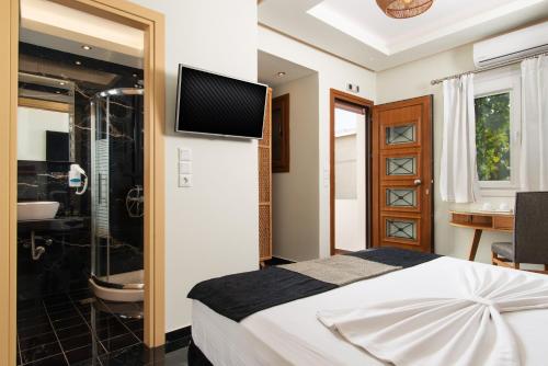1 dormitorio con cama, ducha y TV en Angelica's Deluxe Rooms in Adamas, en Adamas