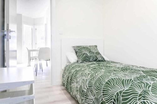 Schlafzimmer mit einem Bett mit einer grünen und weißen Bettdecke in der Unterkunft Apartamento Roncudo Planta Baja in A Coruña