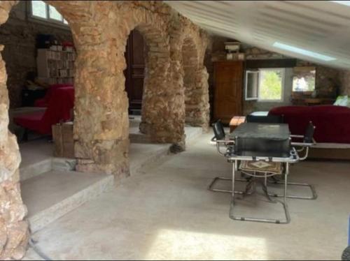 Habitación con mesa y sillas en un edificio de piedra en RELAIS EQUESTRE DE LA CHEVALIERE SAUVAGE en Tourves