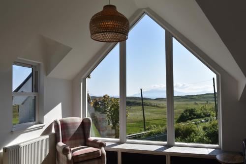 a room with a chair and a large window at Hillside House in Elgol