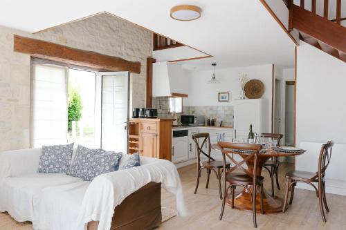 een woonkamer met een bank en een tafel en een keuken bij Ferme des Goupillières in Maisons