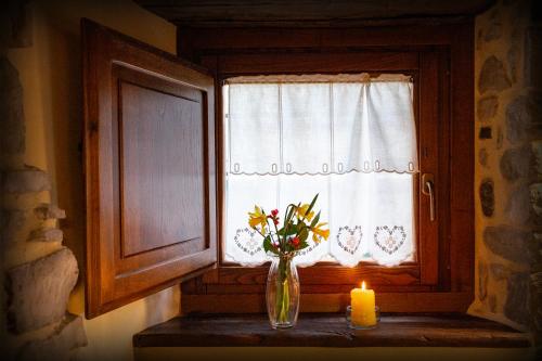 a vase of flowers sitting on a window sill with a candle at Canto del Fiume in Ortignano Raggiolo