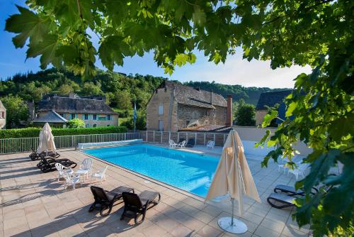 a swimming pool with chairs and a house at L'HÔTEL DES BAINS - Salles-la-Source in Salles-la-Source