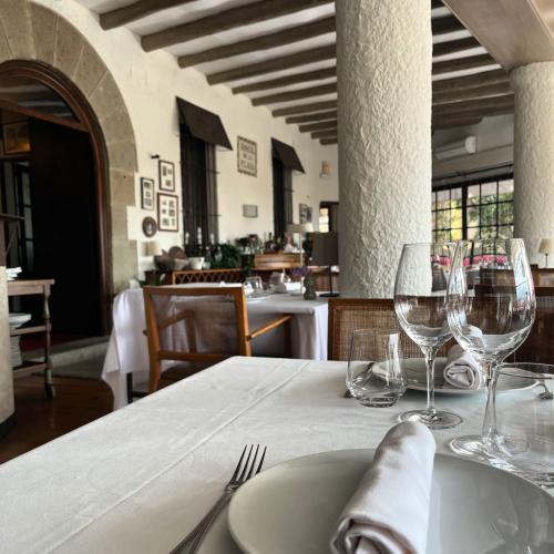 a table with a plate and wine glasses on it at Hostal de la Plaça - Hotel Boutique in Cabrils