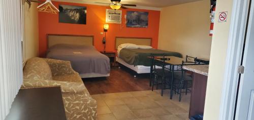 a room with two beds and a couch and a table at Sunparlor Motel in Leamington