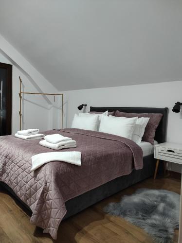 een slaapkamer met een groot bed en handdoeken bij Casa din livada Borlova in Borlova