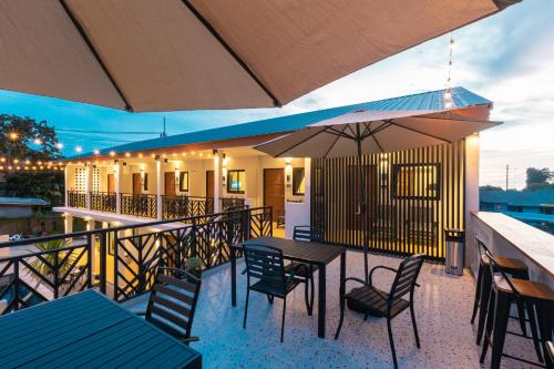 a patio with tables and chairs and an umbrella at The Chu’s Boutique Hotel in Khao Lak