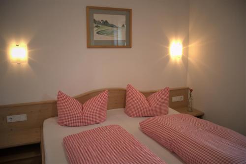 a bedroom with a bed with two red pillows at Ferienwohnungen Kir Royal in Krün