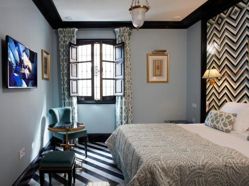 1 dormitorio con cama, ventana y silla en Triana House, en Sevilla