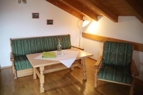 a table with two green chairs and a bottle on it at Ferienwohnungen Kir Royal in Krün