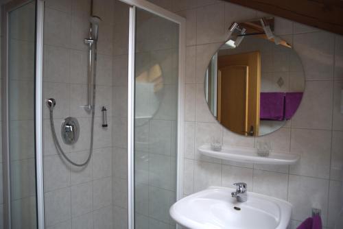 a bathroom with a shower and a sink and a mirror at Ferienwohnungen Kir Royal in Krün