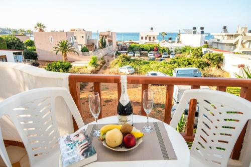 a table with a plate of fruit and a bottle of wine at Alexandra Apartments in Stalida