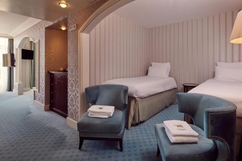 a hotel room with two beds and a chair at Van der Valk Palace Hotel Noordwijk in Noordwijk aan Zee