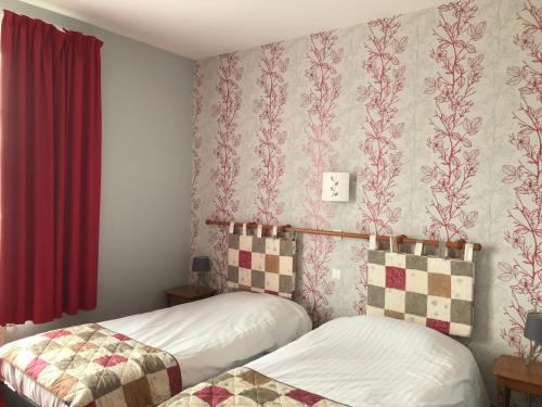 um quarto com 2 camas e uma cortina vermelha em Logis La Villa des Houx em Aumale