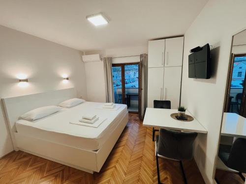 a bedroom with a bed and a table and a desk at Apartments Buljanovic in Pag