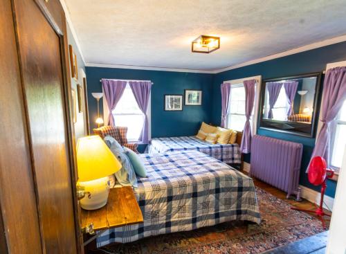 a bedroom with two beds and a table with a lamp at Home Inn The Heart of the Finger Lakes in Geneseo