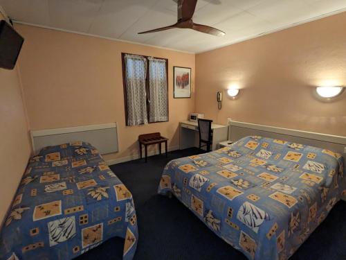 Habitación de hotel con 2 camas y escritorio en Hotel des Voyageurs, en Millau