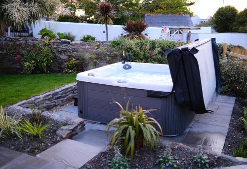 uma banheira de hidromassagem situada num jardim com em Newly renovated cottage with hot tub em Portreath