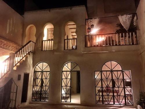 a building with arches and windows at night at Riad Dar El Caid - Palais XIII Siecle in Tozeur
