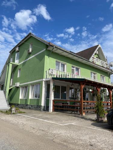a large green building with a balcony on a street at Pensiunea Simina in Caransebeş