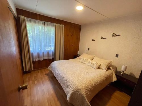 Un dormitorio con una cama grande y una ventana en Cabañas Kernayel en Pucón