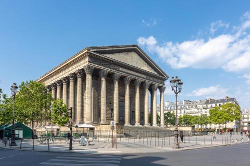 un grand bâtiment avec colonnes dans une rue de la ville dans l'établissement Sweett - Pavillon Madeleine, à Paris