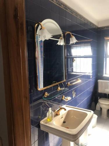 a blue tiled bathroom with a sink and a mirror at Duplex em casa inteiro. 4 quartos. Bem localizada. in Bragança