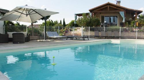 une piscine avec un parasol, une table et des chaises dans l'établissement Villa privative avec grande piscine au coeur de la Drôme, à Allex
