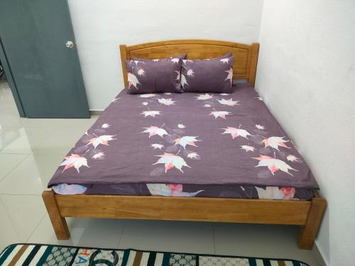 Bett mit lila Daunendecke mit Vögeln darauf in der Unterkunft Dina Homestay B in Pasir Puteh