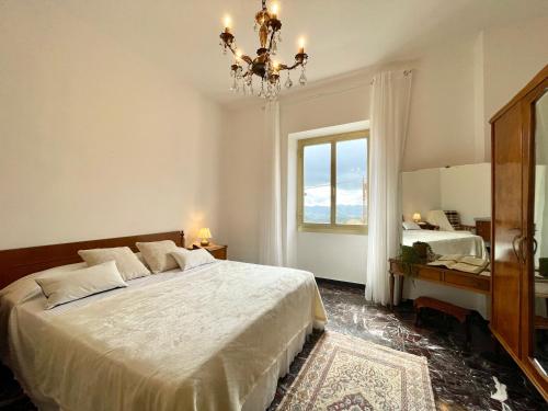 a bedroom with a large bed and a chandelier at [Menosio] La casa di Ermelinda - Relax in Arnasco