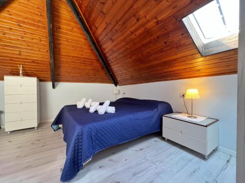 1 dormitorio con cama azul y techo de madera en Casa Max & Lory by Holiday World en Cogoleto